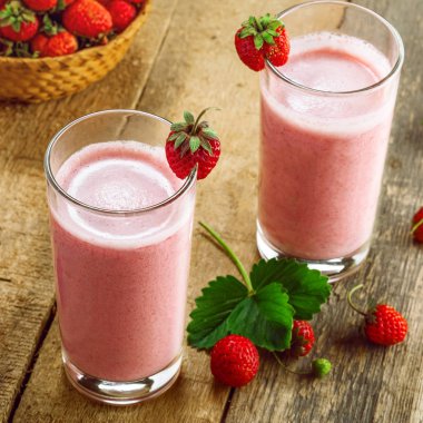 Rustik ahşap bir masa üzerinde taze olgun çilek milkshake yapılmış. Sağlıklı kahvaltı sağlıklı meyve içmeye.