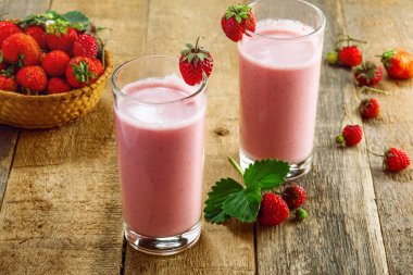 Ahşap bir masa üzerinde taze çilekli milkshake. Sağlıklı meyve güler yüzlü içki.
