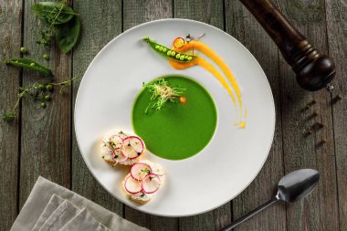 Kremalı bezelye çorbası bir RIM çorba plaka. Rustik ahşap bir masa üzerinde klasik Avrupa gıda.