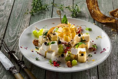 Parmesan, gouda, gorgonzola, brie, camembert ve üzüm, fesleğen ve meze karışımı ile diğer peynir peynir tabağı kümesi. Lezzetli peynir tabağı ahşap bir masa üzerinde.