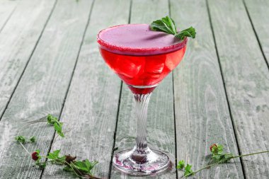 Ahududu, nane, martini, votka ve buzdan yapılmış donmuş bir bardak alkollü kokteyl. Kırsal bir masada alkollü içecek..