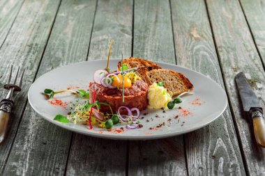Bir tabakta tost ekmek ve salata ile lezzetli tartar. Çiğ etten yapılan sağlıklı öğle yemeği. Klasik Fransız mutfağı. 