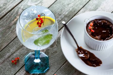 Alkolik cin ve tonik kokteyl, ahşap bir masada tatlı çikolatalı mus..