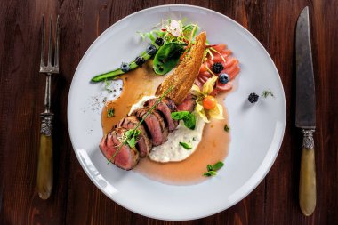 Gourmet orta pişmiş et, sos ve taze salata. Et filetosu ve kırsal bir masada taze sebzelerden yapılmış sağlıklı bir yemek. Üst görünüm.