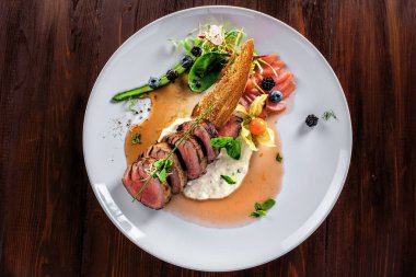 Orta pişmiş biftek madalyonları, soslu ve salatalı. Öğle yemeği için et ve sebzeden yapılmış lezzetli sağlıklı yiyecekler. Üst görünüm.