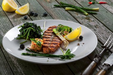 Izgara somon balığı bifteği ve sebze salatası. Kırsal bir masada balık ve sebzelerden yapılmış lezzetli sağlıklı bir yemek..