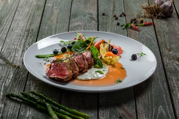 Lezzetli orta pişmiş biftek, sos ve salata. Et fileto ve sebzeden yapılmış gurme yemeği. Lezzetli sağlıklı yemek..