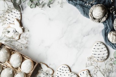 Paskalya süslemeleri mermer arka planda fotokopi alanı ile. Gri boyanmış yumurtalar, el yapımı zencefilli kurabiye ve okaliptüs yapraklarıyla hazırlanma. İyi tatiller. Üst görünüm