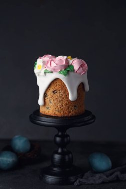 Paskalya pastası, üzerinde pembe kremalı güller olan koyu gri desenli arka planda ahşap siyah duruş. Tatil konsepti. Paskalya ilhamı. Boşluğu kopyala