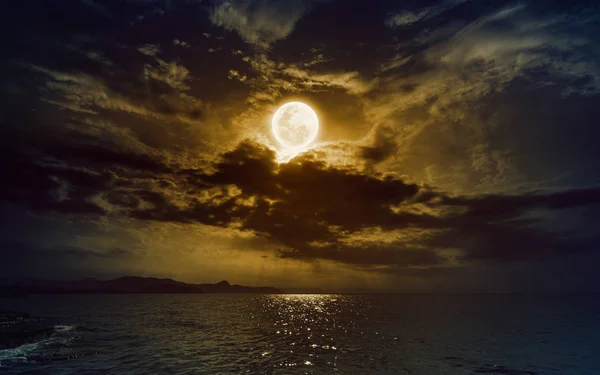 Висхідний жовтий повний місяць у темному нічному небі з відображенням у воді — стокове фото