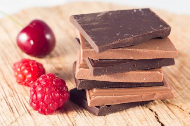 Süt ve koyu çikolata piramit ahşap masa üzerinde. Ahududu ve