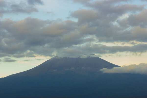 Active volcano Popocatepetl, blue sunrise clouds on top