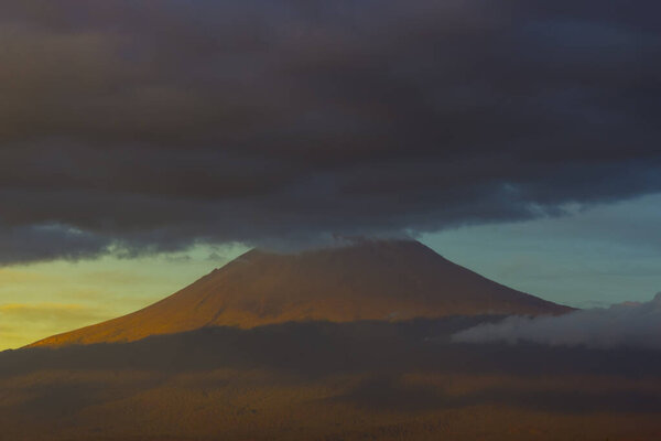 Active volcano Popocatepetl,blue sunrise clouds on top