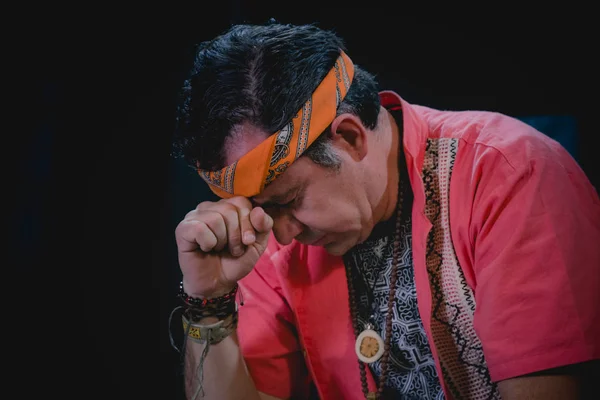 Shaman man, sorcerer, giving thanks duringPre-Hispanic ritual in Healing and cleaning with medicinal plants in Mexico, with black background