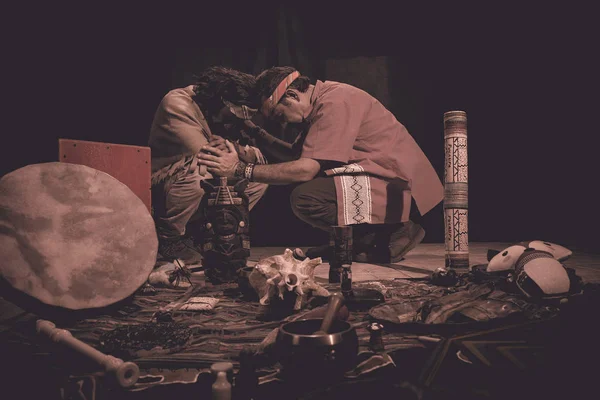shaman or sorcerer men giving sangha medicine, ayahuasca, during prehispanic ritual on black background