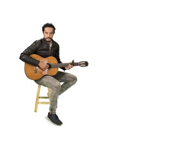 Rock yıldızı ceketli, akustik gitar çalan çekici Latin bir adam.