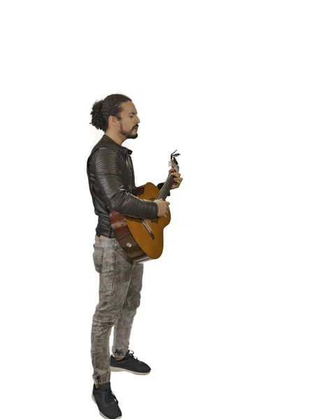 Привлекательный латинский мужчина в куртке рок-звезды, сидя, играя на акустической гитаре, взять с вершины — стоковое фото