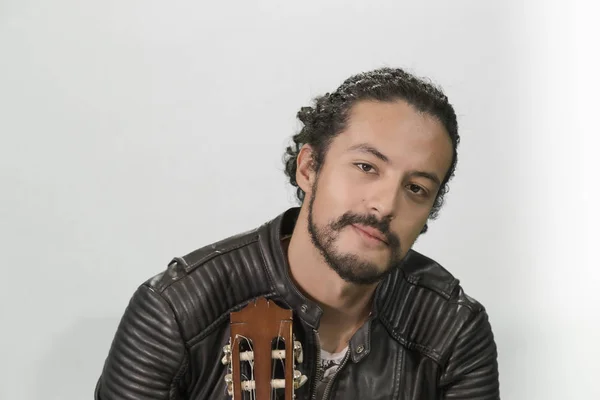 Retrato de atractivo latino joven en chaqueta rocker, sobre fondo blanco, con guitarra acústica — Foto de Stock