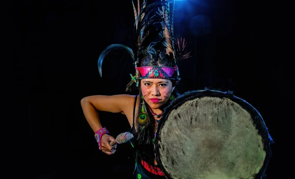 Close up of young woman Teotihuacana, Xicalanca - Toltec in black background, with traditional dress dance with a trappings with feathers and drum — ストック写真