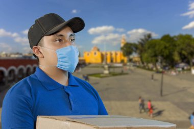 Ev teslimatı, online sipariş. Üniformalı bir adam, tıbbi bir maske ve kutulu lastik eldivenler, elinde bir paket, Meksika sokaklarında.