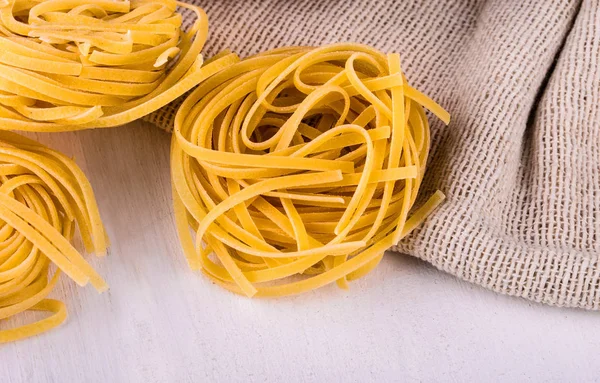 Round spaghetti on sackcloth and  white table — Stock Photo, Image