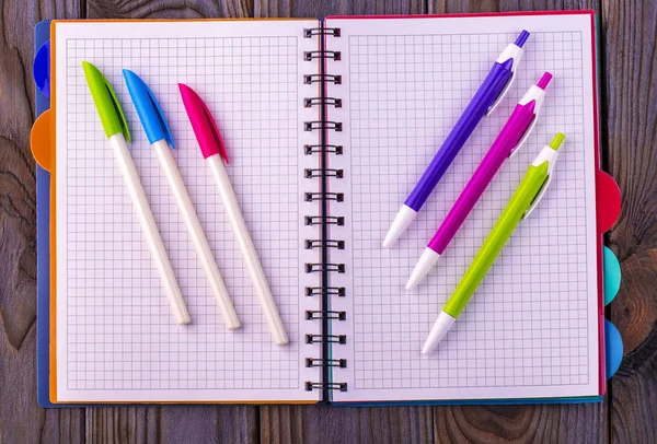 Bloc-notes et stylos colorés sur fond en bois — Photo