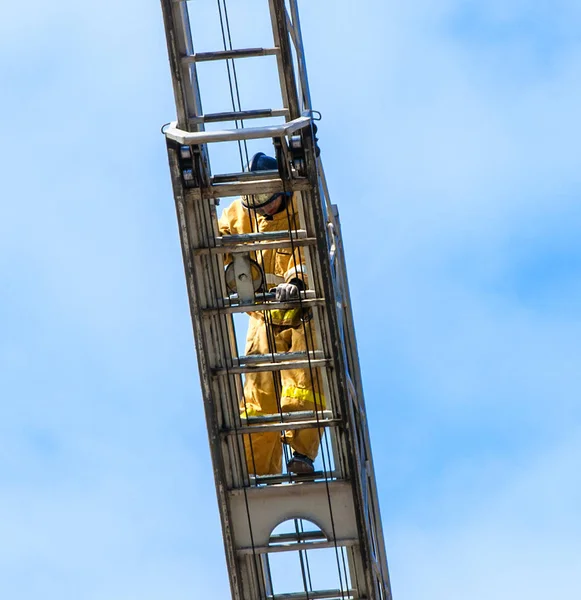 Bombero en entrenamiento subir con las escaleras de incendios . —  Fotos de Stock