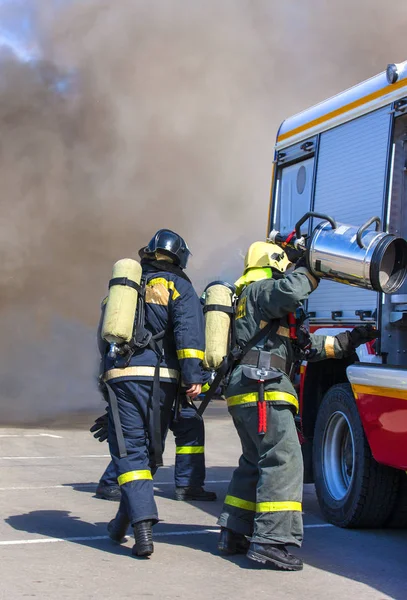 Les pompiers de l'équipe éteignent un incendie dans la fumée avec l'aide de o — Photo