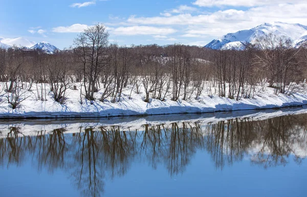 Nehir, volkan, karla kaplı orman ve erken baharda mavi gökyüzü — Stok fotoğraf
