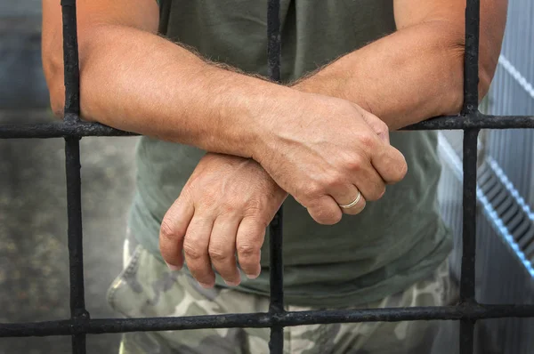 Mani di un uomo dietro le sbarre prigioni — Foto Stock
