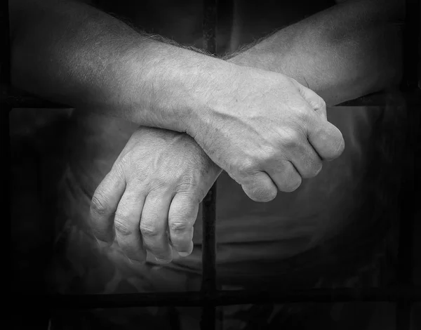 Hands of a man behind jail prisons — стоковое фото