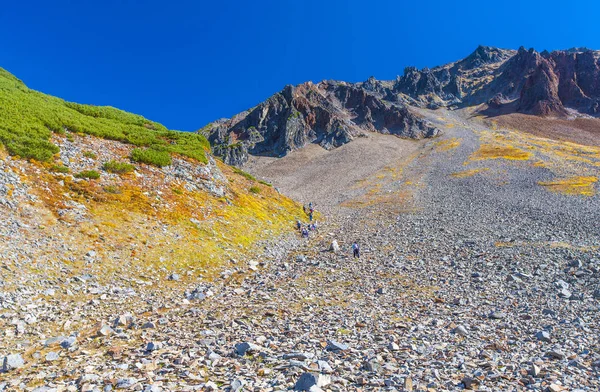 Stone slope of the volcano with walking tourists. — Stock Photo, Image