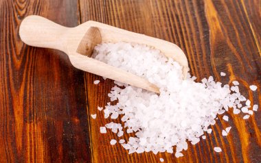 tahta kaşık bir tablo içinde deniz tuzu.