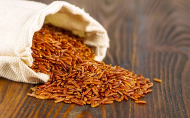 Ahşap masa üzerinde kırmızı kargo pirinç ile çanta.