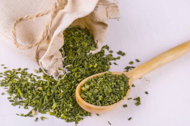 tahta kaşık ve bir çanta içinde yemek pişirmek için baharat yeşil.