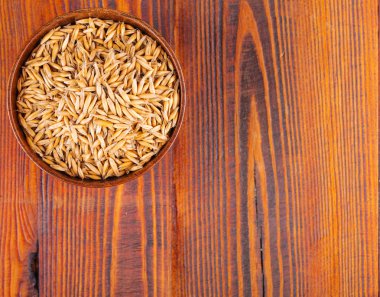 Yulaf kulakları kaynaklanıyor Kupası koyu kahverengi ahşap arka plan üzerinde