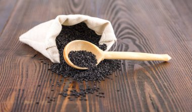 çuval ve ahşap bir masa kaşık siyah susam.