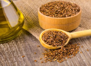 Ahşap bir yüzey üzerinde kahverengi keten tohumu ve keten tohumu yağı 
