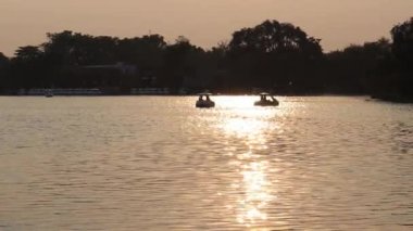 silhouette of boat floating in the lake and reflection at sunrise time.