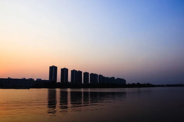 城市景观现代公寓楼附近的一个湖泊在日落的黄昏 云天背景和水的反射为背景 — 图库照片