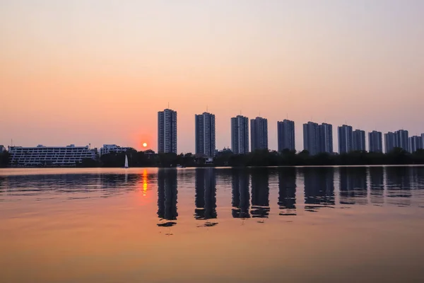城市景观现代公寓楼附近的一个湖泊在日落的黄昏 云天背景和水的反射为背景 — 图库照片