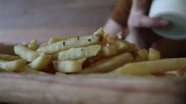 Lokantadaki masada tabaktan patates kızartması alan ellerin yakın çekimi. Fast food, sağlıksız yemek, insanlar ve abur cubur konsepti..