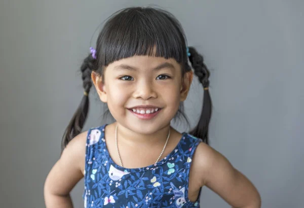 Feliz e engraçado menina asiática sorrindo sobre fundo cinza — Fotografia de Stock