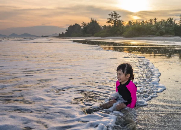Asian or Thai little girl sitting on the beach in evening — Stock Photo, Image