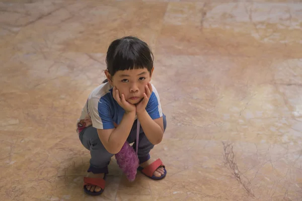 Маленькая азиатка, сидящая на полу и делающая несчастное лицо — стоковое фото