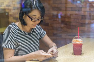 Kahve dükkanında smartphone kullanan kadın pencereden görüntüleme