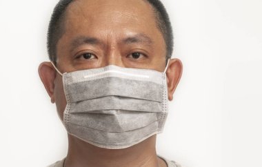 Orta yaşlı Asyalı adamın yüzünü kapatın. Virüs ya da hastalığı önlemek için tıbbi maske takın. Beyaz arkaplandaki izole görüntü. Gri renkli maske takan adam, kameraya bakan gözler..