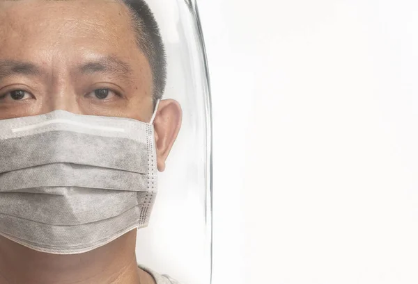 Close up face Asian man wearing medical mask, stay in glass shield or protector. Concept creative design for disease or virus protection. Space for text, isolated image on white background.