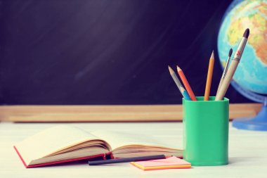 bir arka plan bulanık yazı tahtası ve küre üzerinde kalem ve fırça yanında kitap açık / bekleyen öğrenciler