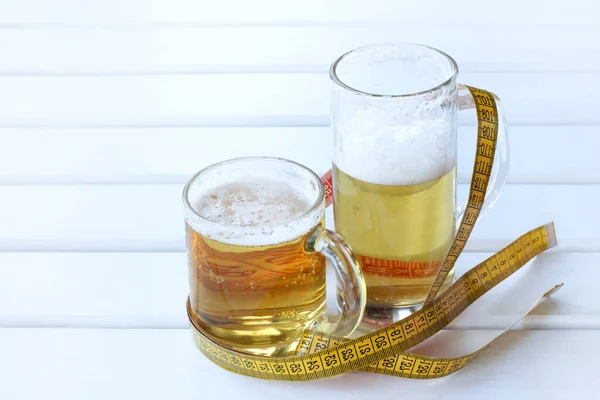 large and small glasses of frothy drink wrapped flexible ruler / excessive alcohol consumption